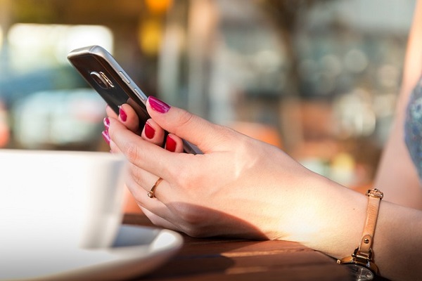 庭木剪定:スマホでリサーチする赤いネイルの女性