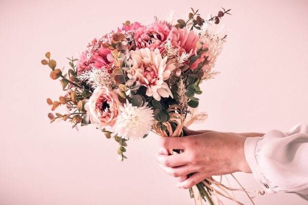 花の定期便：ピンク系の花束をもつ女性の手